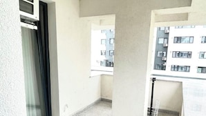 Varanda com vista para um prédio, uma janela e uma porta.