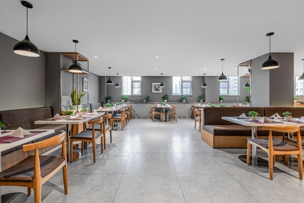 Un restaurante espacioso con varias mesas y cabinas, ventanas amplias e iluminación colgante.