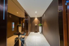 A modern hotel lobby with a reception desk, a digital elevator display, and potted plants. - Yitel (Guangzhou)