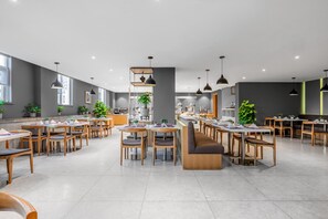 A spacious dining area with multiple tables and chairs, a central seating area with a bench, and a kitchen in the background. - Yitel (Guangzhou)
