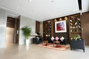 A modern lobby with a reception desk, seating area, and a large abstract painting. - Yitel (Guangzhou)