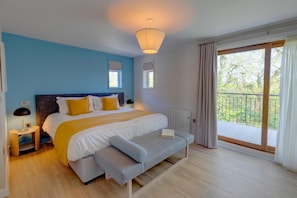 A bedroom with a bed, bedside tables, a bench, a window, and a view of greenery.