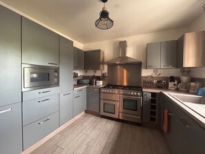 A modern kitchen with stainless steel appliances, grey cabinetry, and a wooden floor. - Country house on the banks of the Eure River – Wooded grounds – Sleeps 10 (Cailly-sur-Eure)