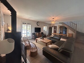 A living room with a sofa, a coffee table, a TV, and a fireplace. - Country house on the banks of the Eure River – Wooded grounds – Sleeps 10 (Cailly-sur-Eure)