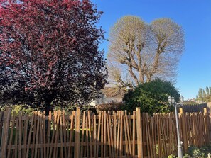 A wooden fence, a tree with red leaves, and a clear blue sky. - Country house on the banks of the Eure River – Wooded grounds – Sleeps 10 (Cailly-sur-Eure)
