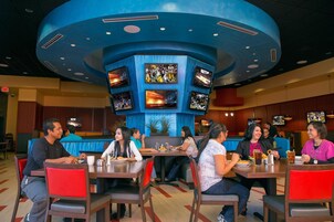 A restaurant with multiple screens displaying sports content, diners seated at tables, and a distinctive blue ceiling.