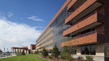 A modern multi-story building with a flat roof, large windows, and a landscaped courtyard.