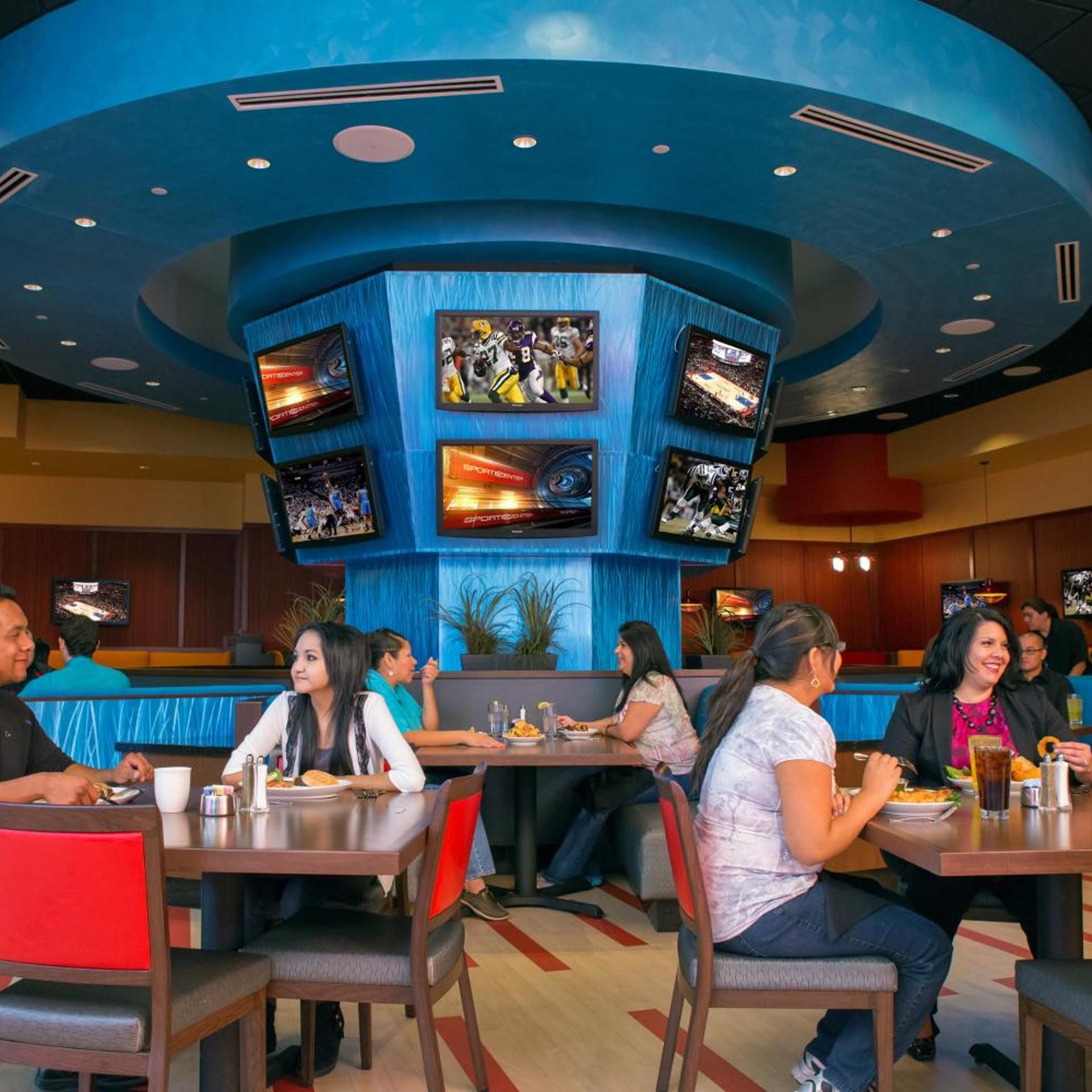 A restaurant with multiple screens displaying sports content, seating arrangements, and a casual dining atmosphere.