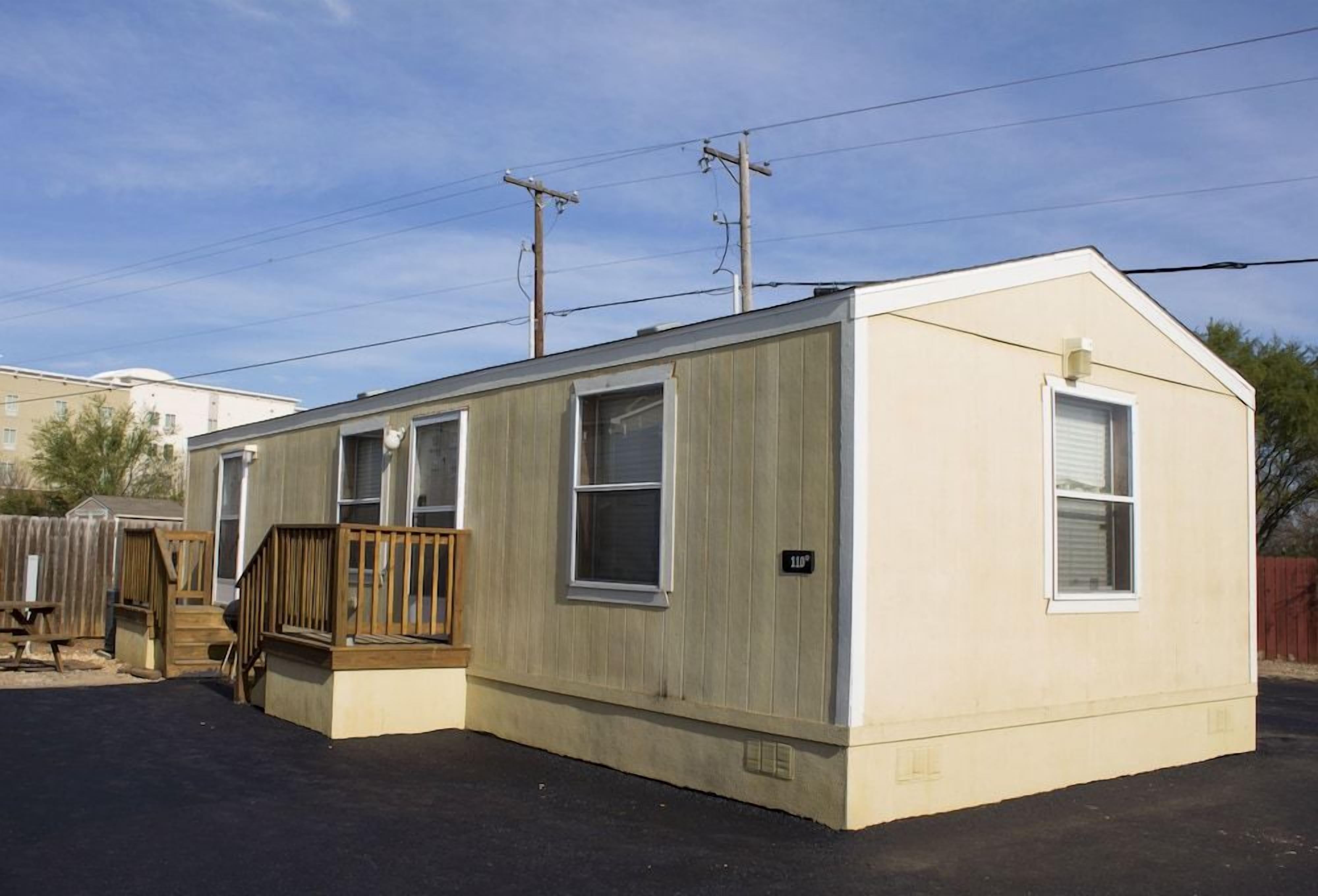 A single-story mobile home with a front porch and a small deck.