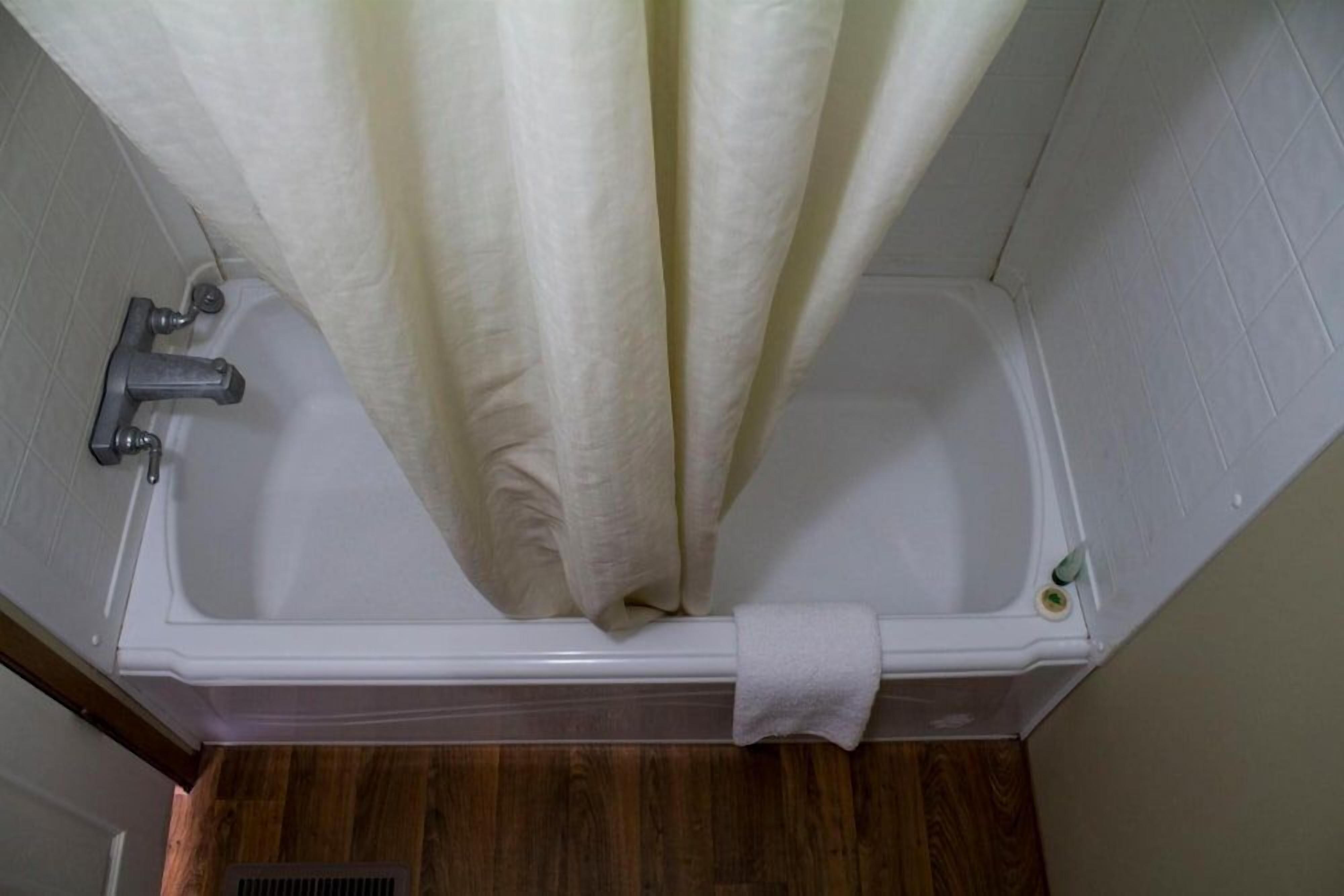 A bathroom with a bathtub, a showerhead, and a towel rack.