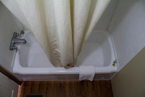 A bathroom with a bathtub, a showerhead, and a towel rack. - Cotulla Mobile Home (Cotulla)