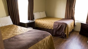 Ett hotellrum med två sängar, ett nattduksbord och en byrå.