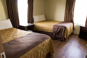 Quarto de hotel com duas camas, uma mesa de cabeceira e um guarda-roupa.
