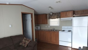 Ett kompakt bostadsutrymme med ett litet kök, en soffa och en matplats.