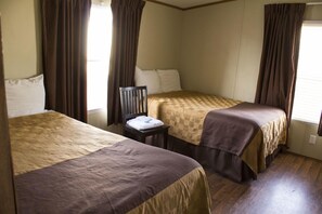 A hotel room with two beds, a nightstand, and curtains. - Cotulla Mobile Home (Cotulla)