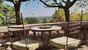 An outdoor seating area with a round table and two cushioned chairs, surrounded by stone steps and a view of the landscape. - Villa Castel Chambres Dhotes (Rillieux-la-Pape)