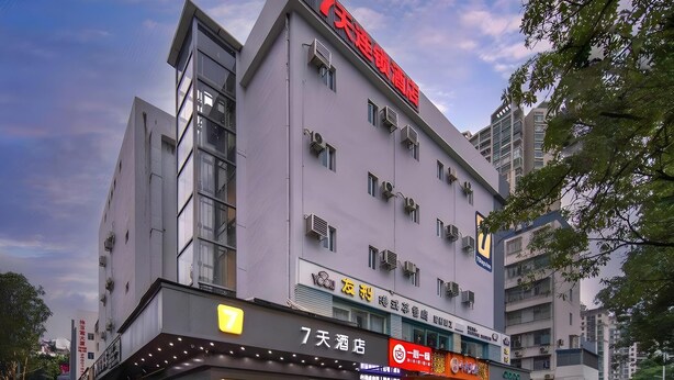 A multi-story hotel with a prominent red sign on the top, multiple windows, and a ground-level restaurant with a yellow sign. - 7 Days Inn Sea World 2nd Branch (Shenzhen)