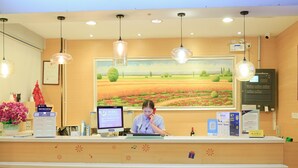 A reception desk with a computer monitor, a telephone, and a framed landscape painting above. - 7 Days Inn Sea World 2nd Branch (Shenzhen)