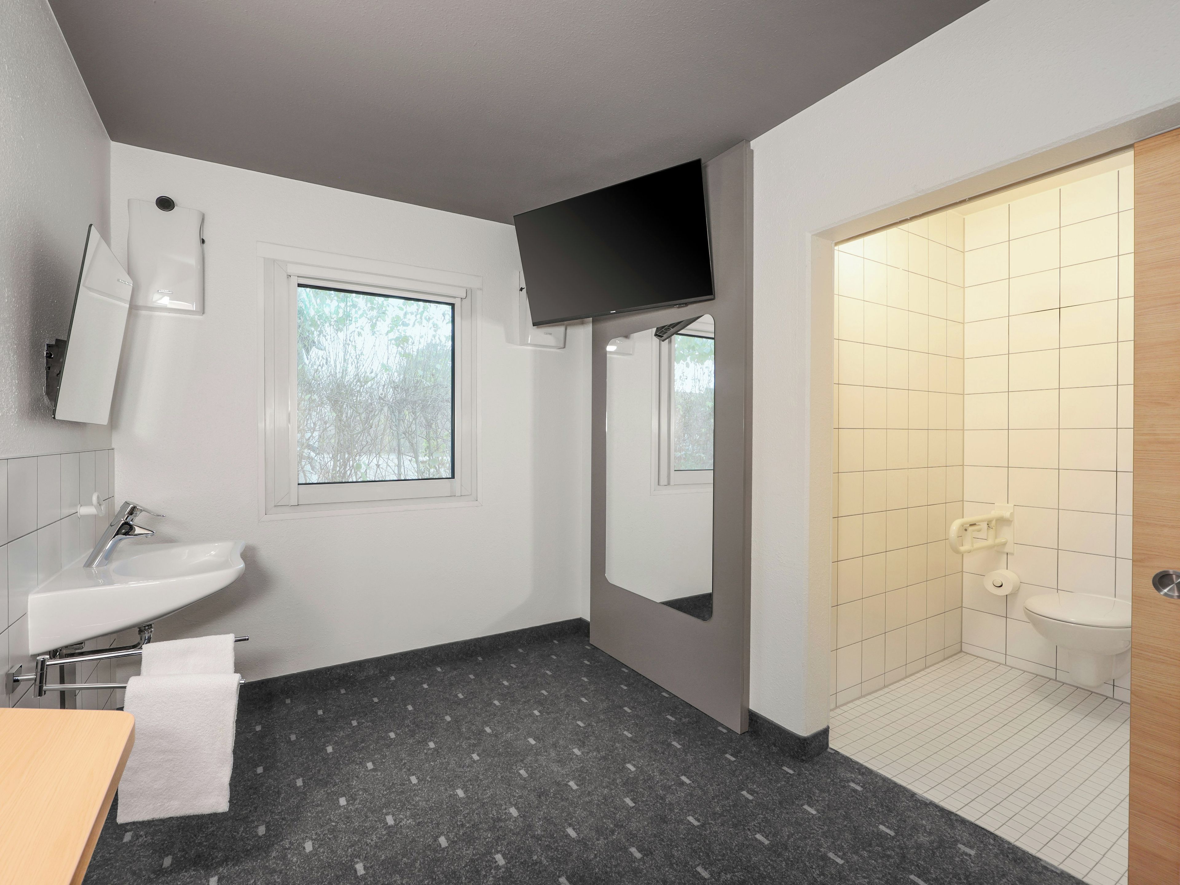 Ein modernes Badezimmer mit Waschbecken, Spiegel und Duschbereich.
