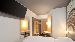 A hotel room with a bed, a mirror, and a wall-mounted TV. - Ibis Budget Berlin Genshagen (Ludwigsfelde)