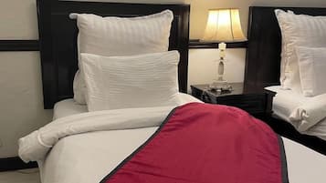 Habitació d'hotel amb un llit, una tauleta de nit amb una làmpada i una manta vermella.