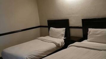 Habitación de hotel con dos camas individuales, una mesita de noche y un aplique de pared.