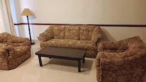 A living room with a sofa set, a coffee table, and a floor lamp. - Shangrila Hotel & Resort Changla Gali (Abbottabad)
