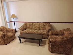 Ein Wohnzimmer mit einer Sofagarnitur, einem Couchtisch und einer Stehlampe.