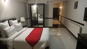 A hotel room with a bed, a nightstand, a lamp, and a view of the hallway. - Shangrila Hotel & Resort Changla Gali (Abbottabad)