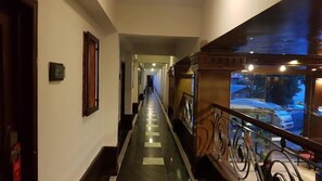 Un pasillo con barandilla de cristal, un extintor y un cuadro en la pared.