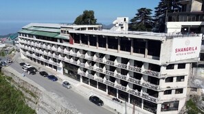 A multi-story hotel with balconies, a sign reading 'Shangrila Hotels & Resorts,' and a view of the surrounding area.