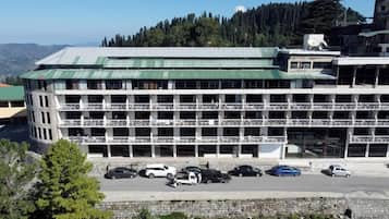 Un immeuble à plusieurs étages doté d’un toit végétalisé, de nombreux balcons et d’un parking où sont stationnées diverses voitures.