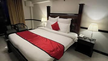 A hotel room with a large bed, bedside tables, a desk, and a chair.