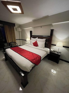 Une chambre d’hôtel avec un grand lit, des tables de chevet, un bureau et une chaise.