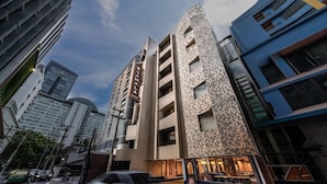 A modern hotel with a unique facade, multiple floors, and a visible restaurant on the ground level. - Court Wing Hotel Sukhumvit Bangkok (Bangkok)