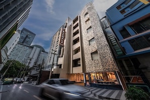 A modern hotel with a unique facade, multiple floors, and a visible restaurant on the ground level. - Court Wing Hotel Sukhumvit Bangkok (Bangkok)