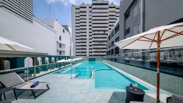 A rooftop pool area with lounge chairs and umbrellas, surrounded by high-rise buildings. - Court Wing Hotel Sukhumvit Bangkok (Bangkok)