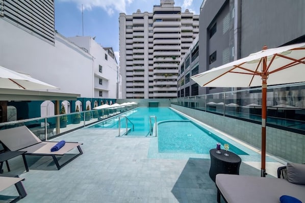 A rooftop pool area with lounge chairs and umbrellas, surrounded by high-rise buildings. - Court Wing Hotel Sukhumvit Bangkok (Bangkok)