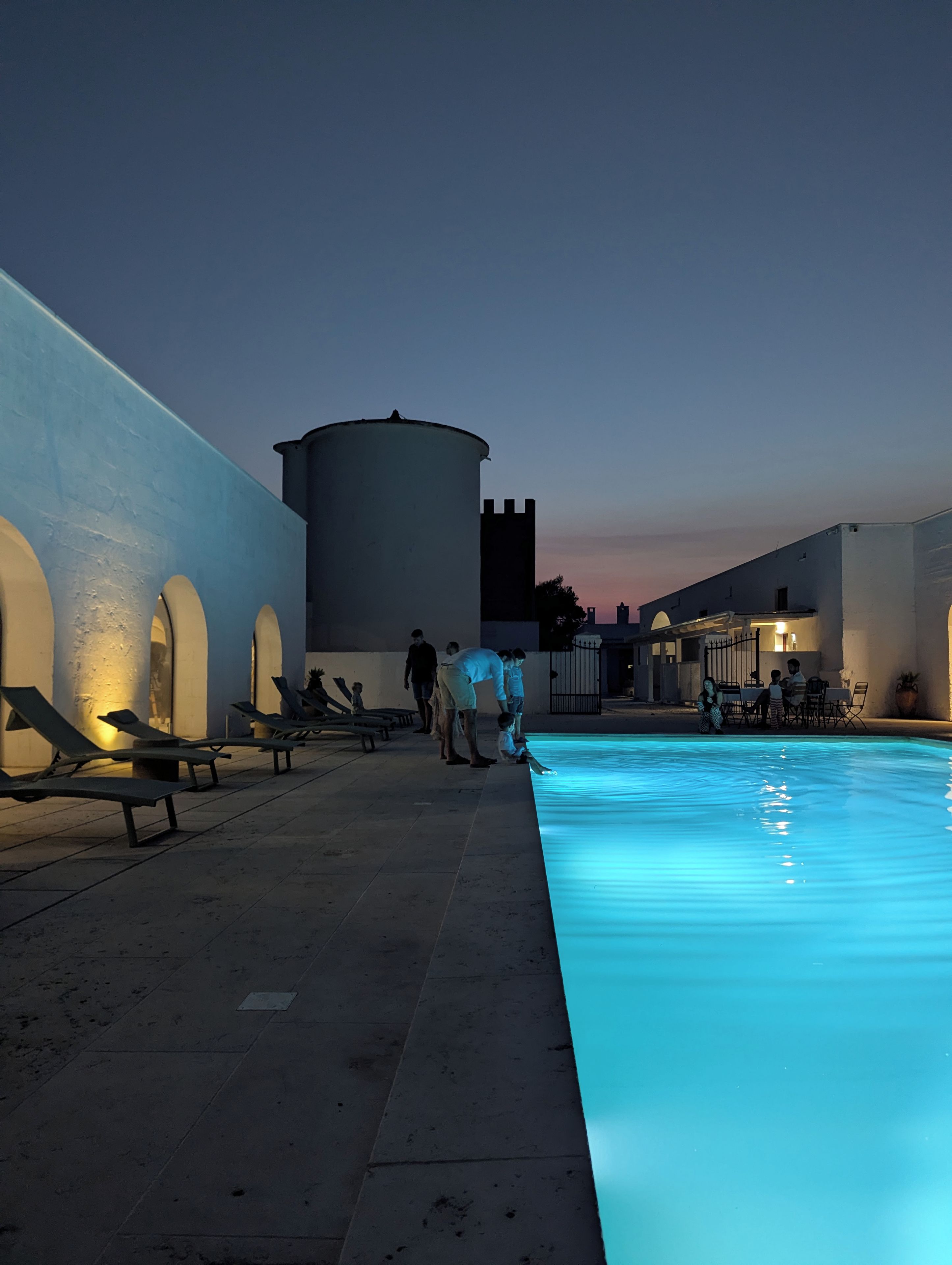 Una piscina con sillones de descanso y una torre de agua.