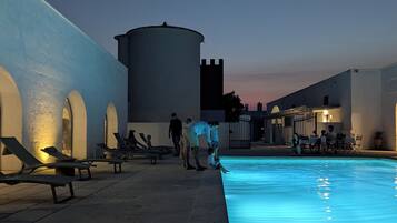 Una piscina con sillones de descanso y una torre de agua.
