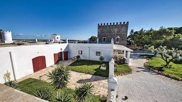 Un patio con una torre, muros blancos y vistas al mar.