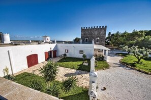 A courtyard with a tower, white walls, and a view of the sea.