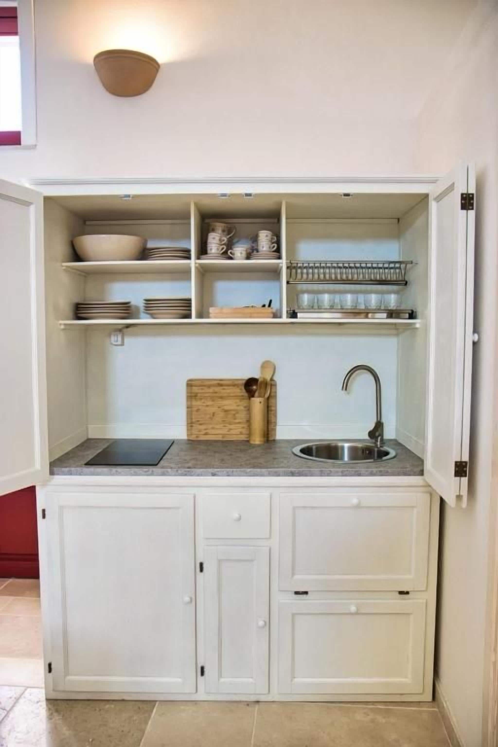 A compact kitchen with white cabinetry, a sink, and a countertop.