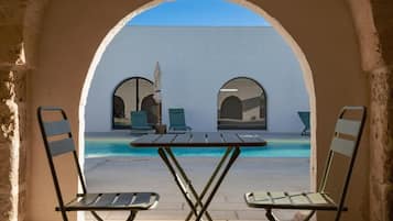 Ein Sitzbereich im Freien mit Pool, zwei Stühlen und einem Tisch, eingebettet in einer Bogenstruktur.