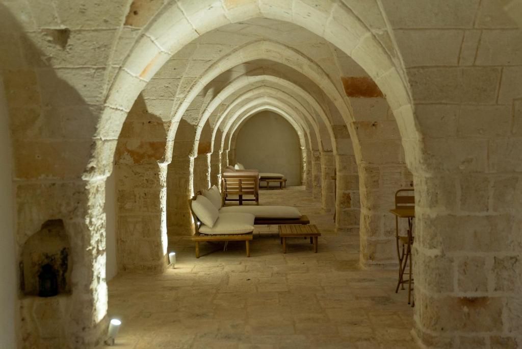 An arched corridor with stone walls, a bench, and a table.