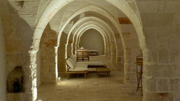 An arched corridor with stone walls, a bench, and a table.