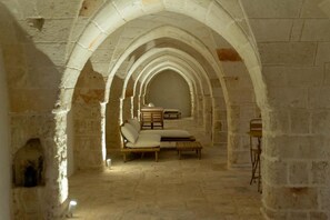 An arched corridor with stone walls, a bench, and a table.