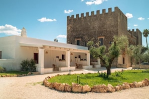 A building with a courtyard, a stone tower, and a white building with outdoor seating.