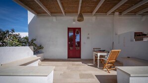 Un portico riparato con una porta rossa, un tavolo e due sedie.