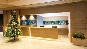A reception area with a Christmas tree, wooden reception desk, and a large window with a city view. - Monti Spa Wellness Hotel Igman (Hadzici)